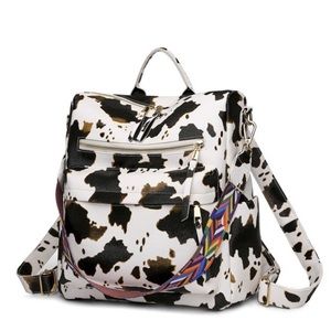 Brown and white cow print backpack with multicolored guitar strap